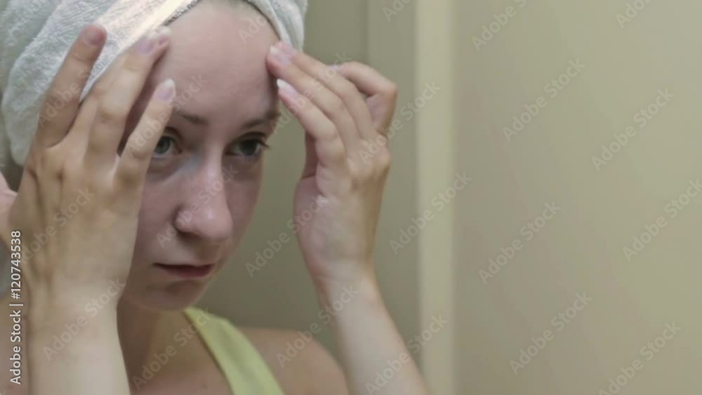 Beautiful woman with towel on head plucking her eyebrows in front of mirror. Beauty and makeup concept Beautiful woman with towel on head plucking her eyebrows in front of mirror. Beauty and makeup concept
