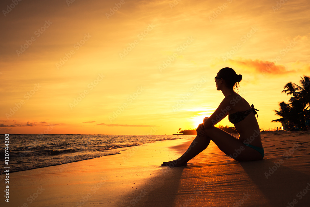 Girl sitting on the beach watching the sunset. 