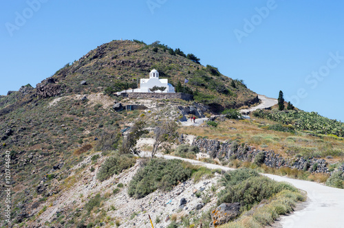 White church on mountain between of towns on Santorini island