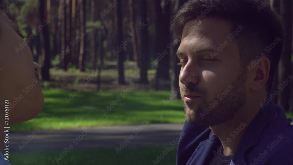 Young man and woman drinking coffee and talking outdoors. Caucasian couple on a date at the park in summer. Pair in love kiss talk eating. Smiling people in morning sunny day. Young man and woman drinking coffee and talking outdoors. Caucasian couple on a date at the park in summer. Pair in love kiss talk eating. Smiling people in morning sunny day.