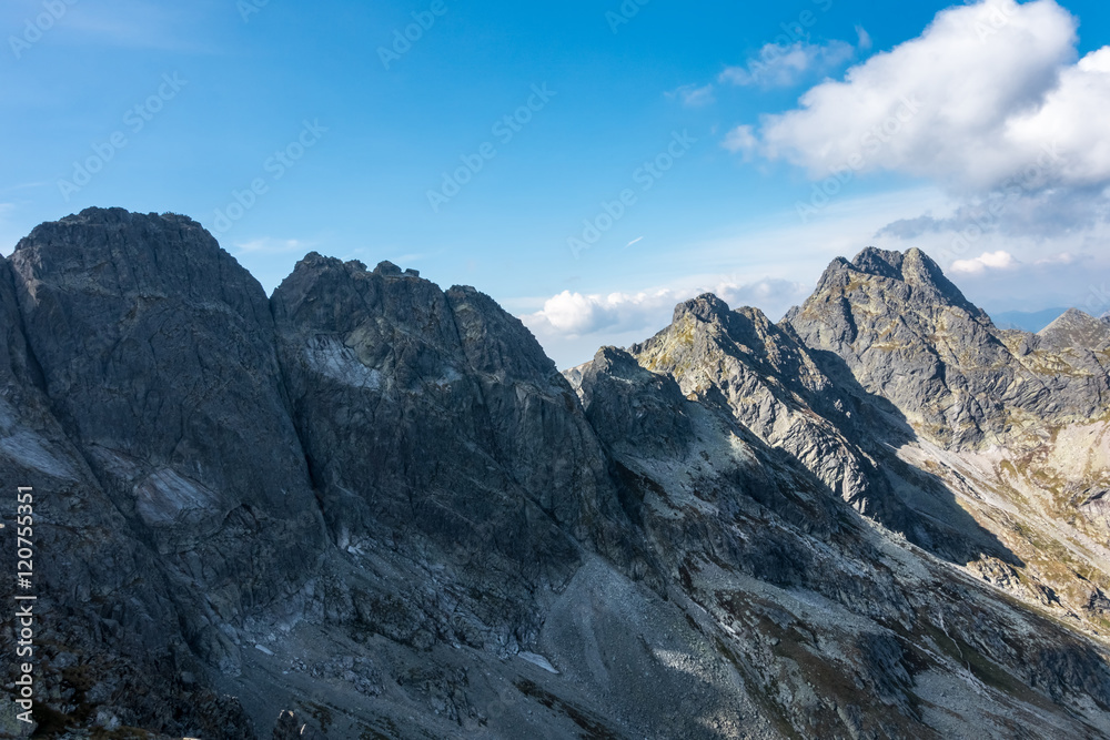 Amazing rocky mountain ridge under blue sky with white clouds