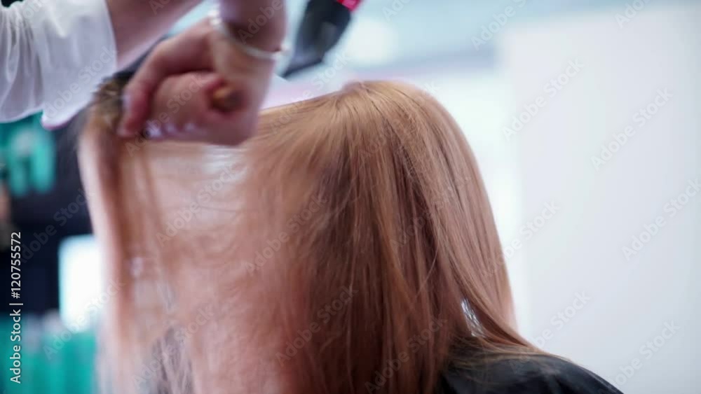 Blow-dry hair. Male hand hairdresser makes hair styling by hairdryer. Woman in a beauty salon. The stylist combing hair and do blow-dry. Professional hairdresser used a hairdryer. Blow-dry hair. Male hand hairdresser makes hair styling by hairdryer. Woman in a beauty salon. The stylist combing hair and do blow-dry. Professional hairdresser used a hairdryer.