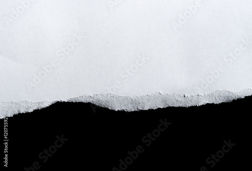 White torn of paper isolated on a black background. © showcake