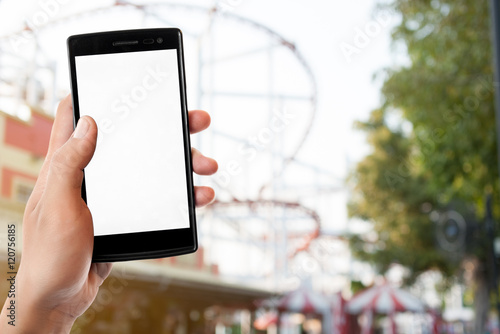 Hand holding smart phone on blurred park, natural background