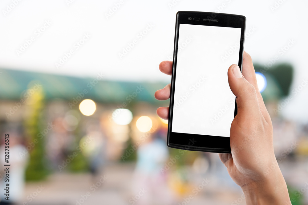 Hand holding smart phone on blurred park, natural background Hand holding smart phone on blurred park, natural background