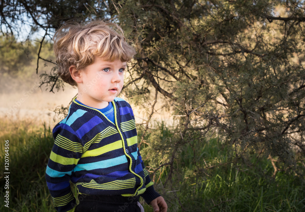 Little blonde boy under tree being pensive Little blonde boy under tree being pensive