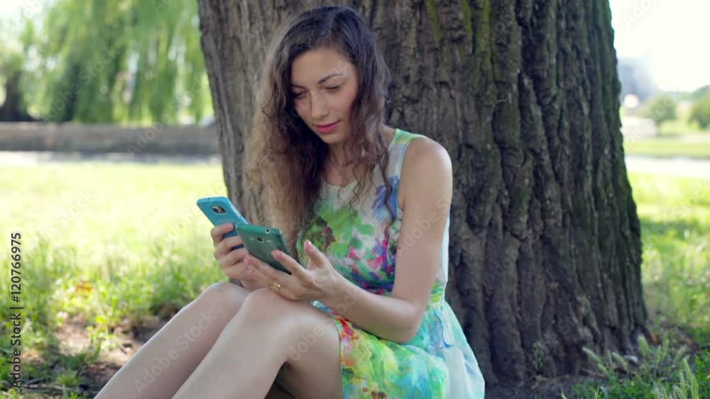 Girl in floral dress using two smartphones while sitting in the park
Girl in floral dress using two smartphones while sitting in the park