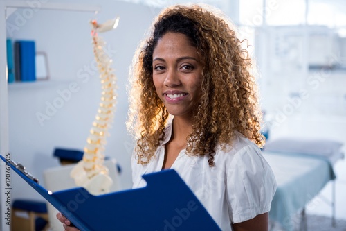 Smiling physiotherapist holding clipboard in clinic photo