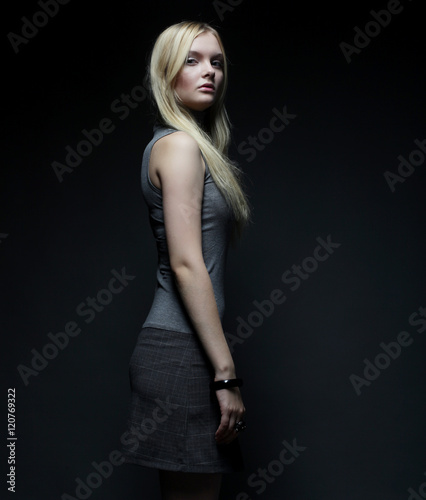 Portrait of beautiful young blonde girl in black dress. 