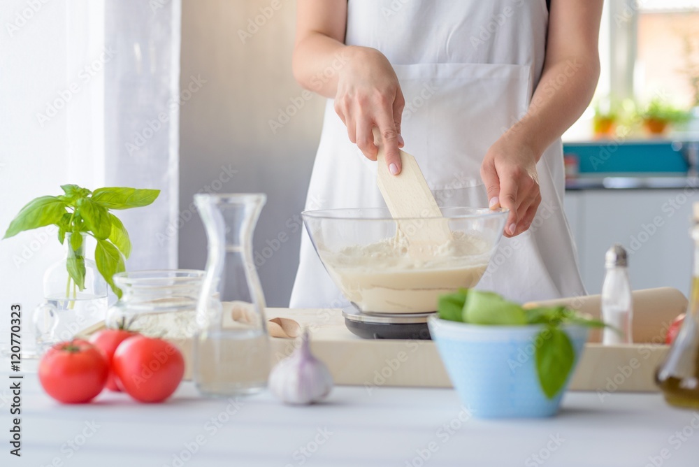 Woman mixing pizza dough with wooden spatula. Woman mixing pizza dough with wooden spatula.