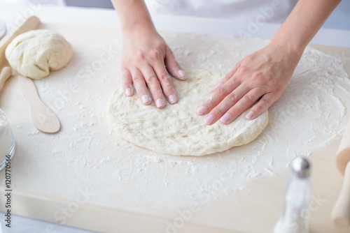 Fotografie, Obraz Woman kneading pizza dough on wooden pastry board.