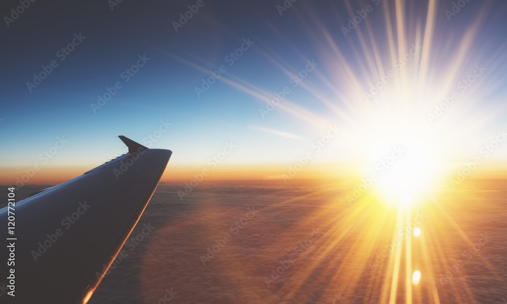 Clouds and sunlight as seen image through window an aircraft. Looking out the window of plane. Airplane in the blue sky at sunrise. View  wing from the inside on background sunset, mockup
