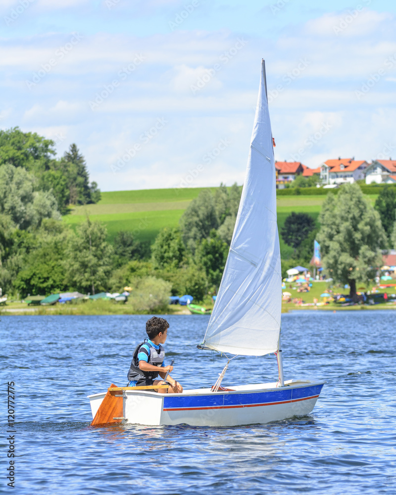 Fototapeta premium kleiner Junge beim Segeln mit seiner Jolle
