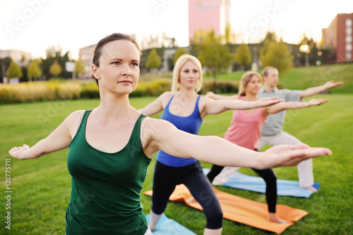 yoga group conducts training outdoors on a background of grass and sunset