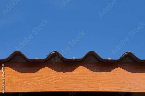 Roof tiles and brown wood wall of a house, Sun and rain protection create warmth to the family on blue sky background