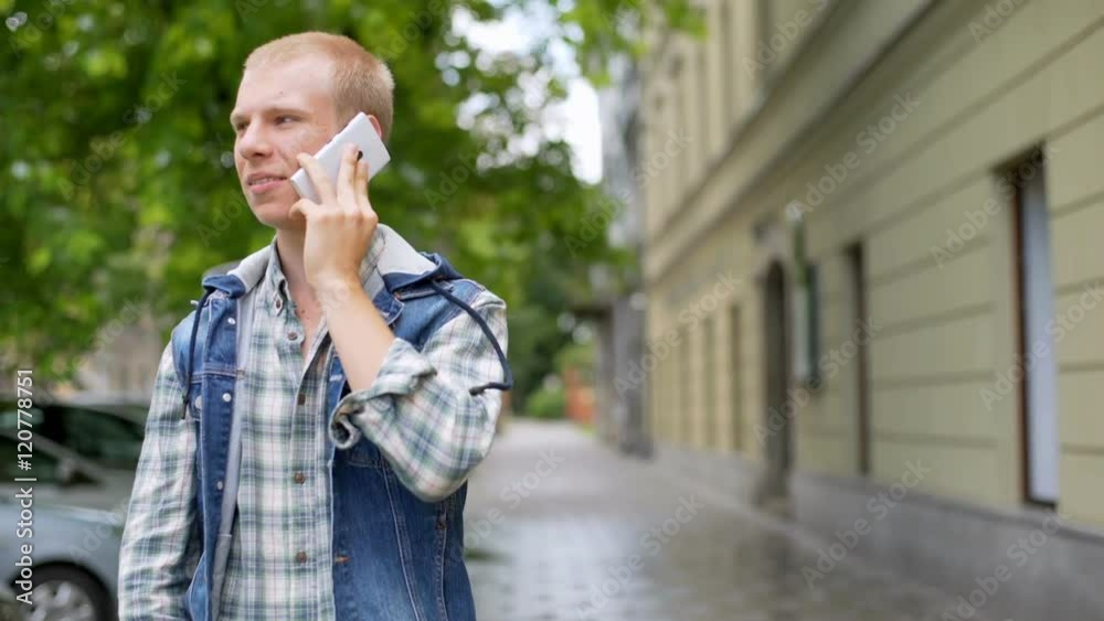 Student standing on the path in the city and chatting on cellphone
