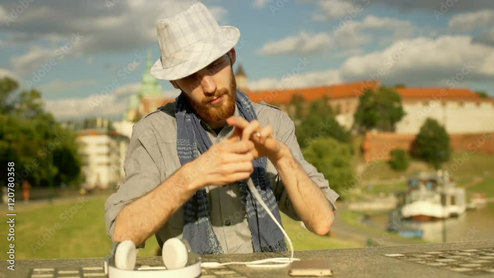 Tourist connecting headphones to the smartphone while sitting next to the castle
Tourist connecting headphones to the smartphone while sitting next to the castle