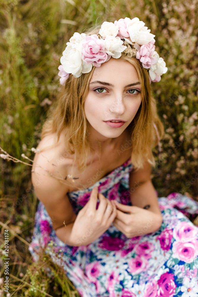 Fototapeta premium Young girl in flower wreath walking in meadow