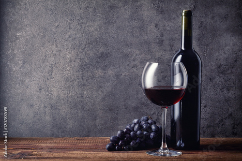 Bottle and glass of red wine and grapes photo