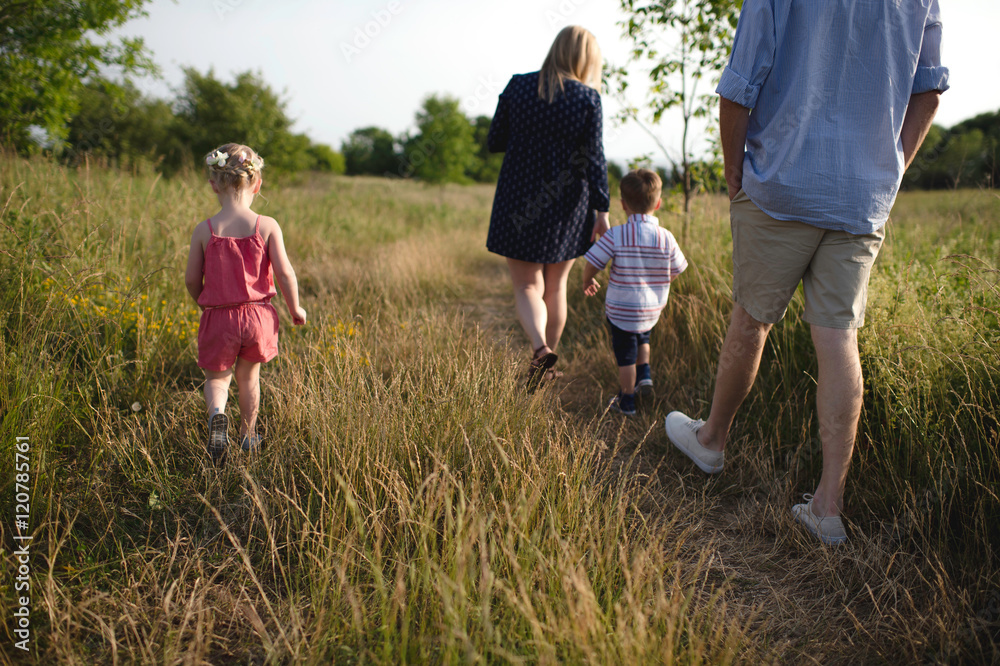 Rear view of mid adult parents strolling in meadow boy and girl Rear view of mid adult parents strolling in meadow boy and girl