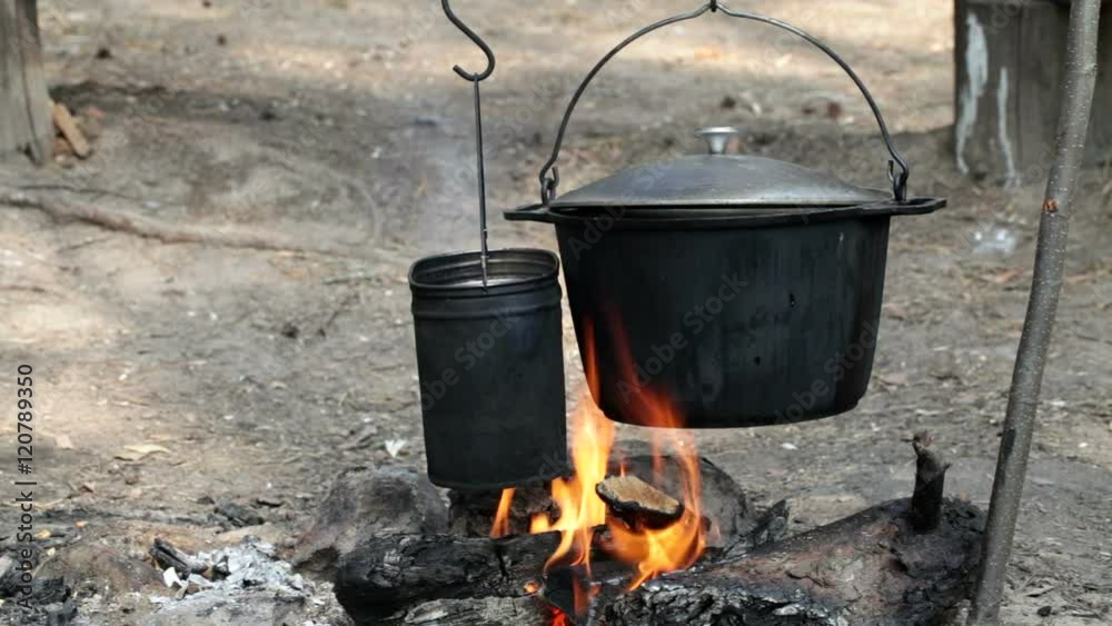 Cooking camp food in a kettle or cauldron on open fire Cooking camp food in a kettle or cauldron on open fire
