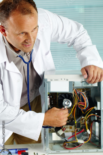 Man examining computer with stethoscope