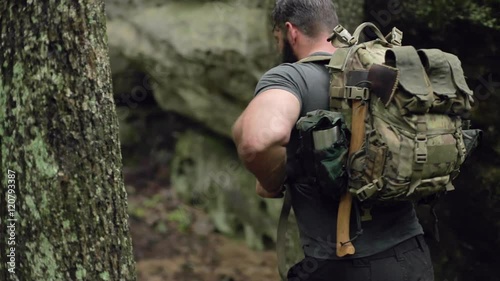 Detail of a male hiker walking through woods in shallow focus and slow motion.