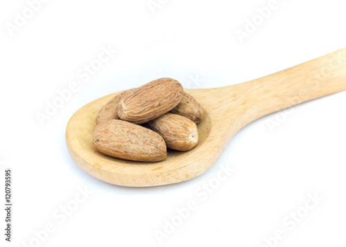 Nutmeg on wooden spoon over white background. photo