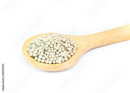 White pepper on wooden spoon over white background