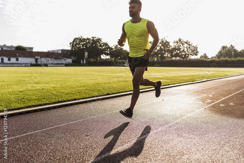 Athlete running on tartan track photo