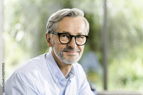 Portrait of smiling man with grey hair and beard wearing spectacles photo