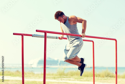 young man exercising on parallel bars outdoors
