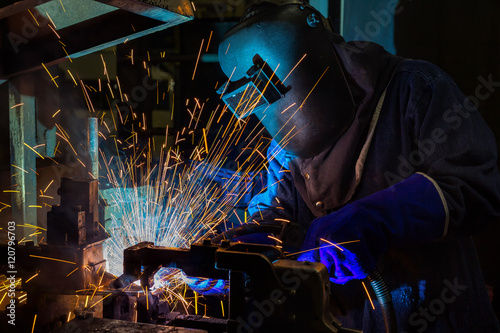 Worker welding automotive part in factory