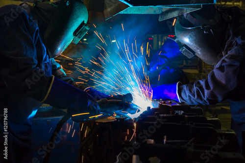 Workers are welding automotive part in factory