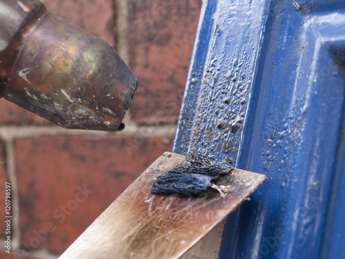 Heat gun being used to strip old paint from kitchen cupboard doors prior to repainting photo