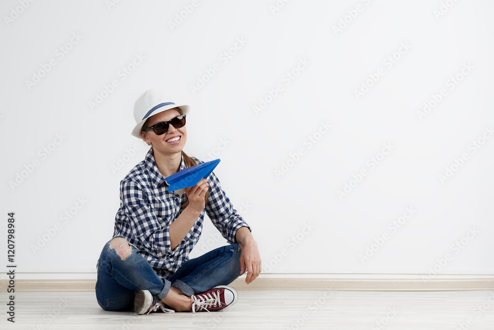 Joyful female holding blue paper plane, dreaming about summer journey. Concept of tourism and vacation. Joyful female holding blue paper plane, dreaming about summer journey. Concept of tourism and vacation.