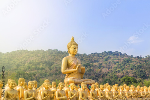big golden buddha statue and many small golden buddha statues sitting in row in temple nakornnayok  thailand.