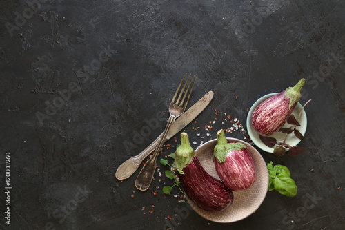 Eggplant varieties in black bowl over dark slate background. Overhead view.