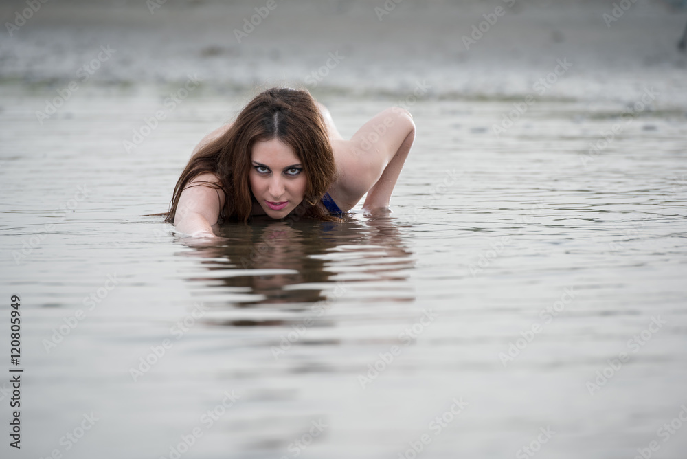 Tall woman with long red hair wear bikini and pose in the sea Tall woman with long red hair wear bikini and pose in the sea