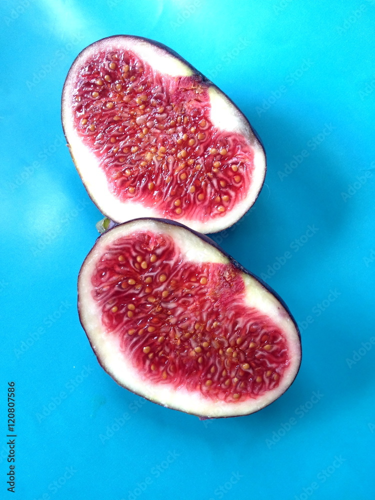 Cut ripe fig fruit on purple light blue background Cut ripe fig fruit on purple light blue background
