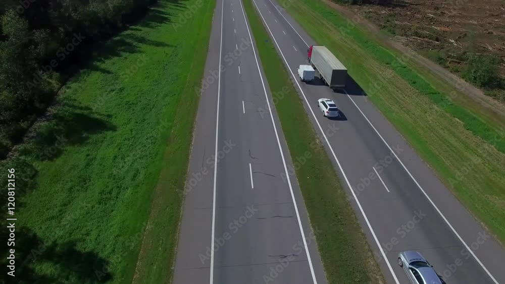 Highway aerial with cars and truck lorry moving aerial view 4k. Four lane local road traffic transport vehicles driving both directions bird eye top above Highway aerial with cars and truck lorry moving aerial view 4k. Four lane local road traffic transport vehicles driving both directions bird eye top above