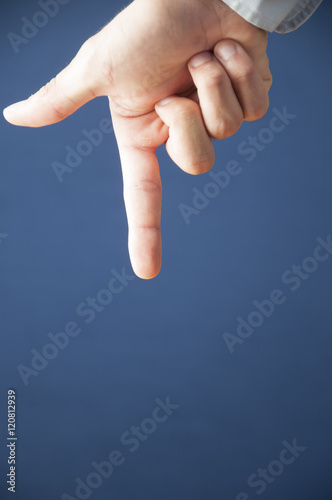 Closeup of male hand pointing down isolated on blue background