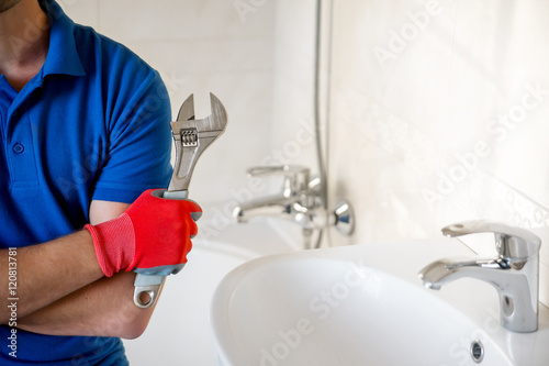 Fotografija plumber with wrench standing in bathroom