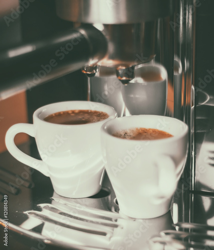 Fresh coffee prepared in the coffee machine. Espresso in small white cups.Vintage style