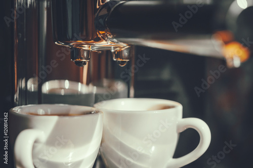 Fresh coffee prepared in the coffee machine. Espresso in white cups.Close-up of drops of coffee.