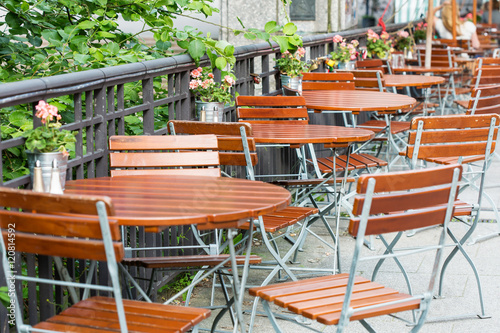 round wooden tables with chairs at summer open air cafe terrace