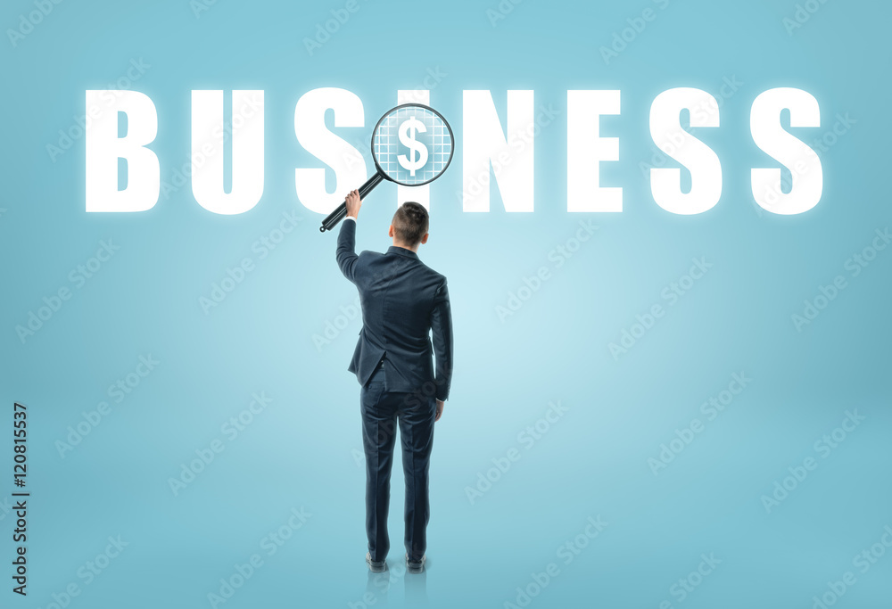 Businessman looking at 'business' word with magnifier and seeing dollar sign Businessman looking at 'business' word with magnifier and seeing dollar sign