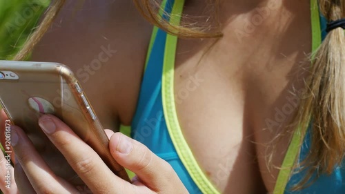 Young attractive woman in a bikini using her phone, in slow motion