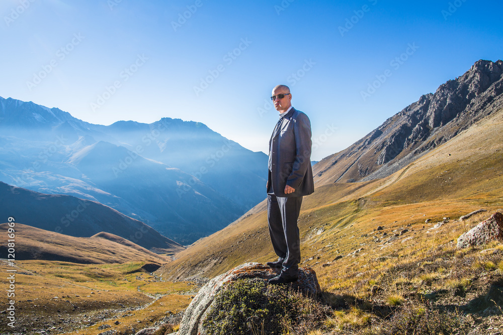 a man in a suit and with a cigarette on the nature, a panorama of mountains, summer