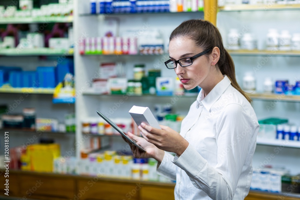 Pharmacist using digital tablet while checking medicine